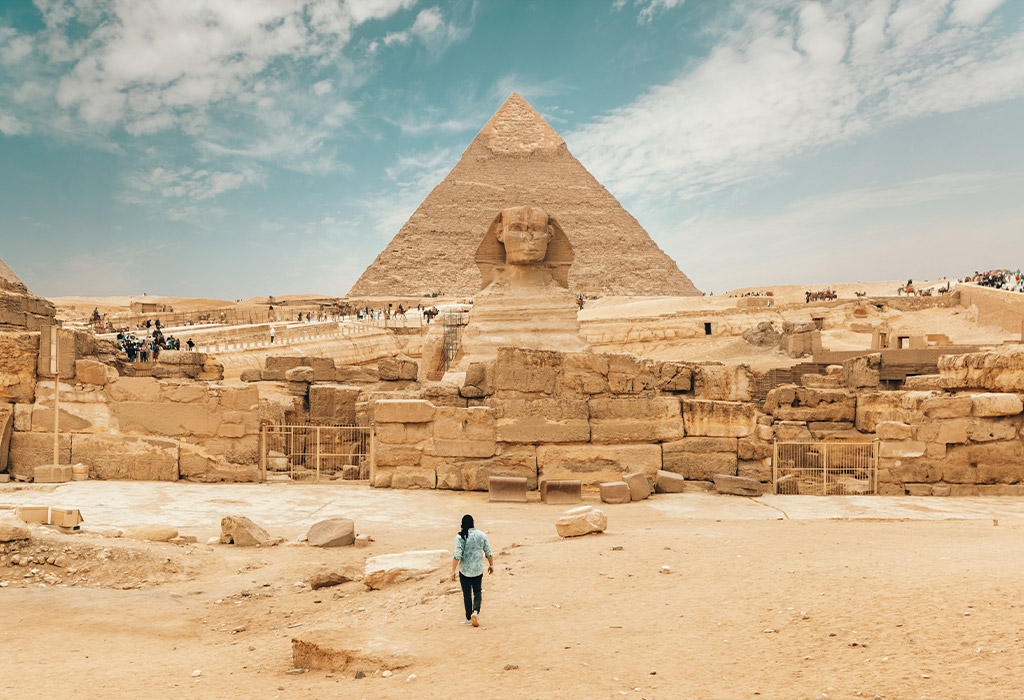person walking towards sphynx in Egypt with Great Pyramid in the background